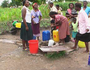 Women collect water from the only water source in their neighbourhood. It is located near an open makeshift sewerage pit.